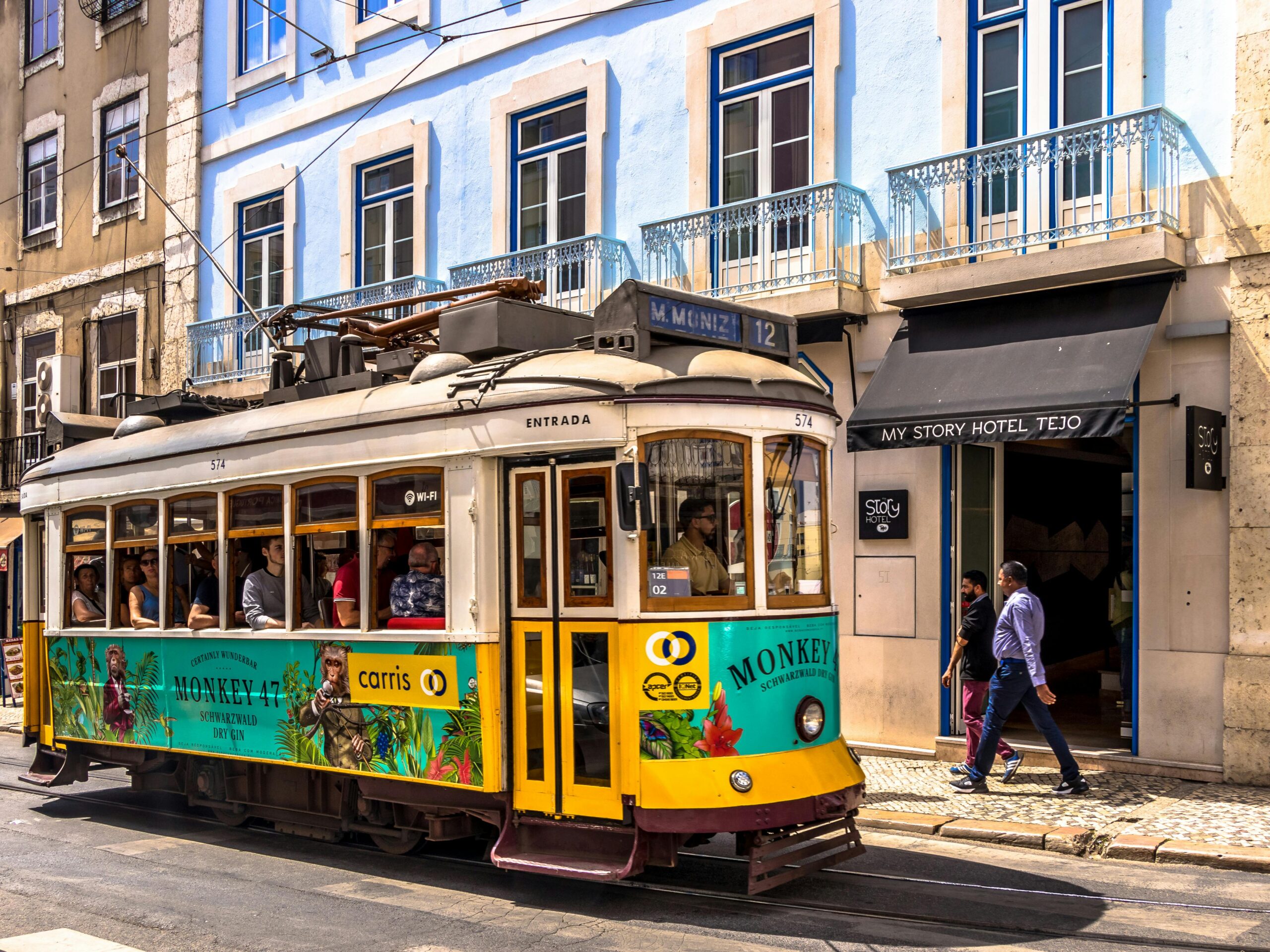 Colorful tram travels in Lisbon's historic city center, a popular tourist attraction.